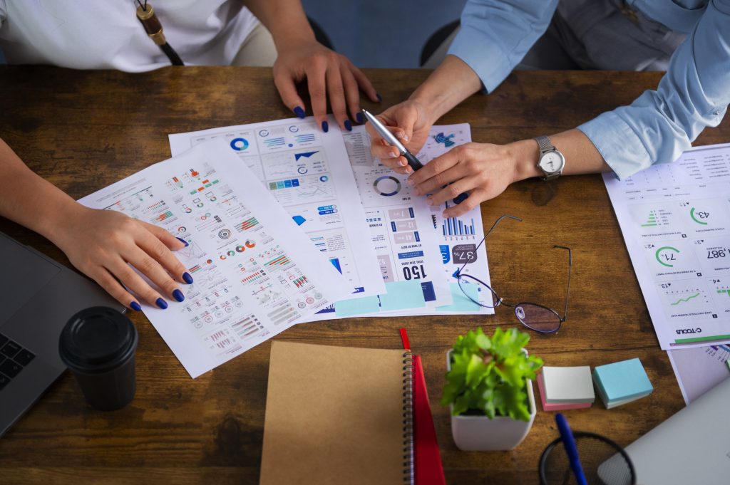 Two professionals analyzing charts and graphs on a wooden desk, showcasing insights from digital marketing services Islamabad.